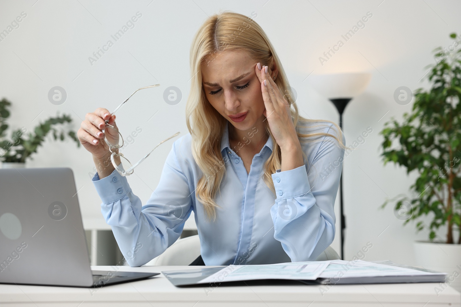 Photo of Overwhelmed woman with glasses at table in office