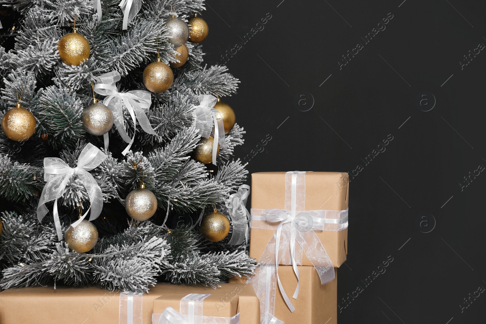 Photo of Decorated Christmas tree and gift boxes against black background