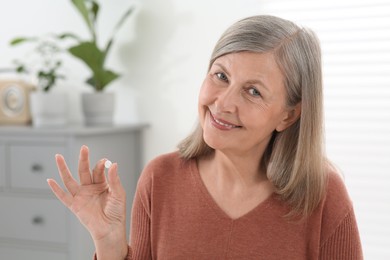 Beautiful senior woman with pill at home