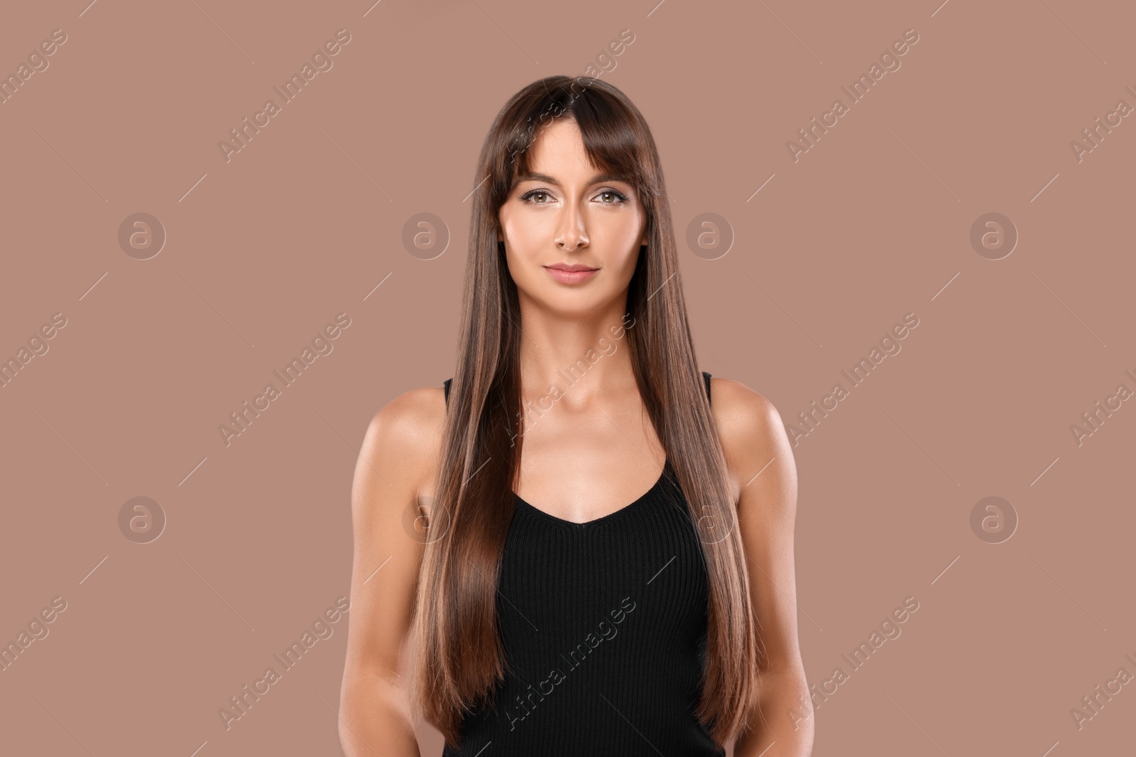 Photo of Hair styling. Portrait of beautiful woman with straight long hair on pale brown background