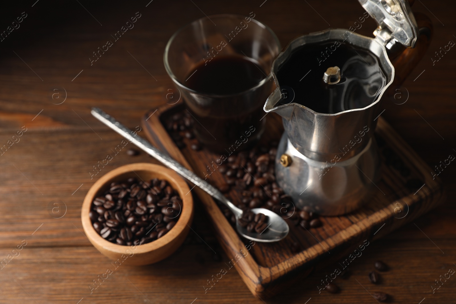 Photo of Brewed coffee, moka pot and beans on wooden table