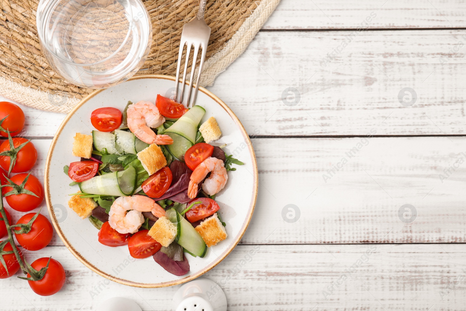 Photo of Tasty salad with croutons, tomato and shrimps served on white wooden table, flat lay. Space for text