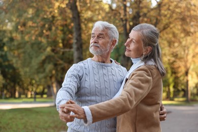 Affectionate senior couple dancing together in autumn park