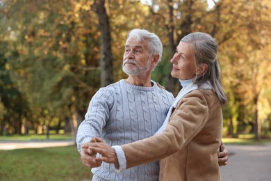 Photo of Affectionate senior couple dancing together in autumn park