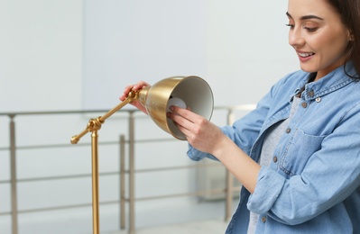 Photo of Woman changing light bulb in lamp indoors