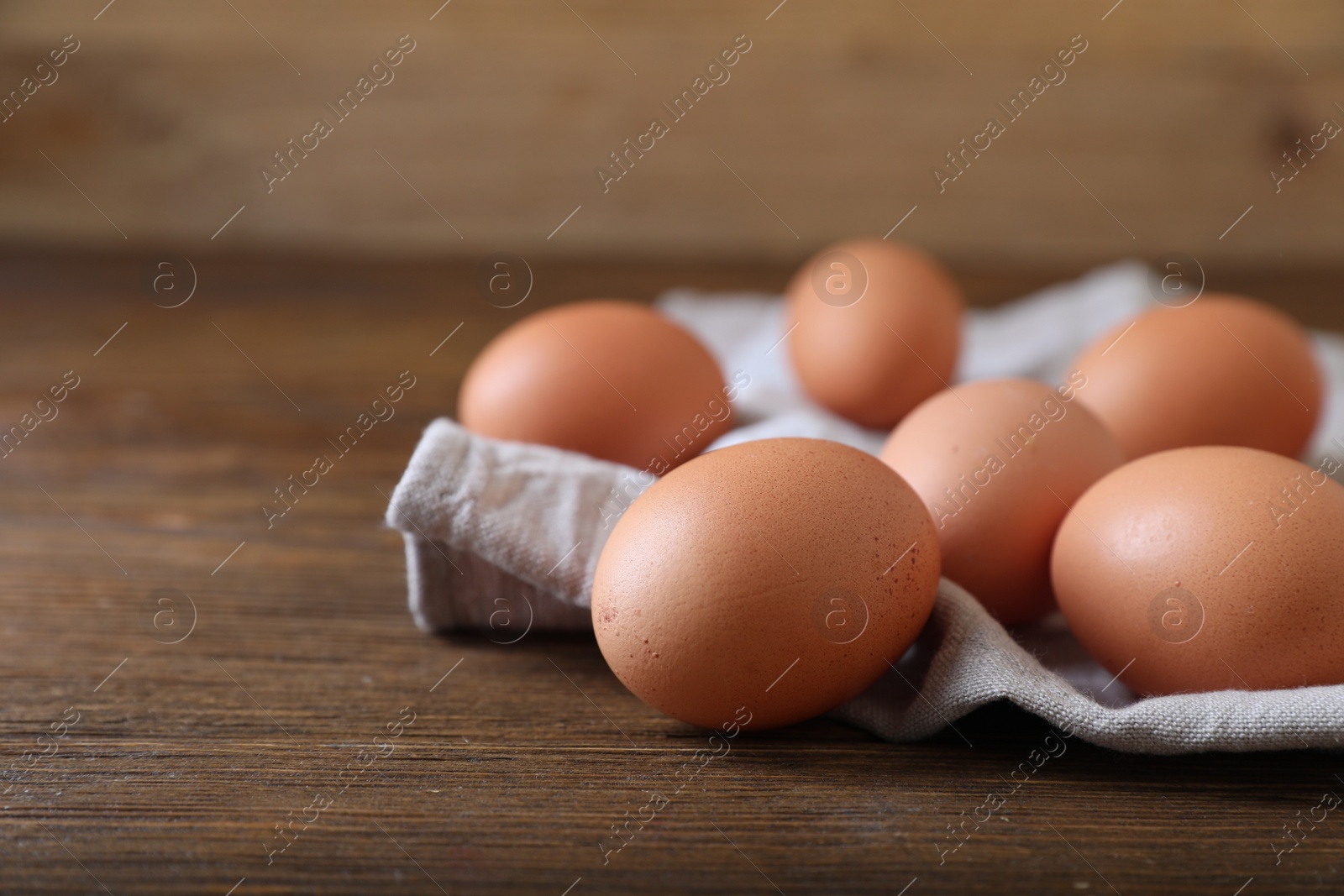 Photo of Raw brown chicken eggs on wooden table, space for text