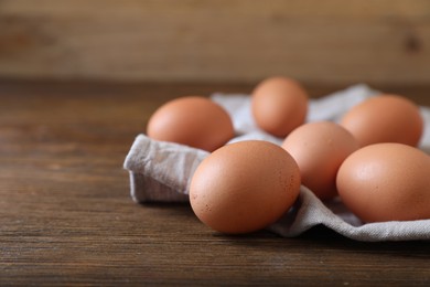 Photo of Raw brown chicken eggs on wooden table, space for text