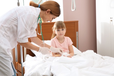 Doctor adjusting intravenous drip for little child in hospital