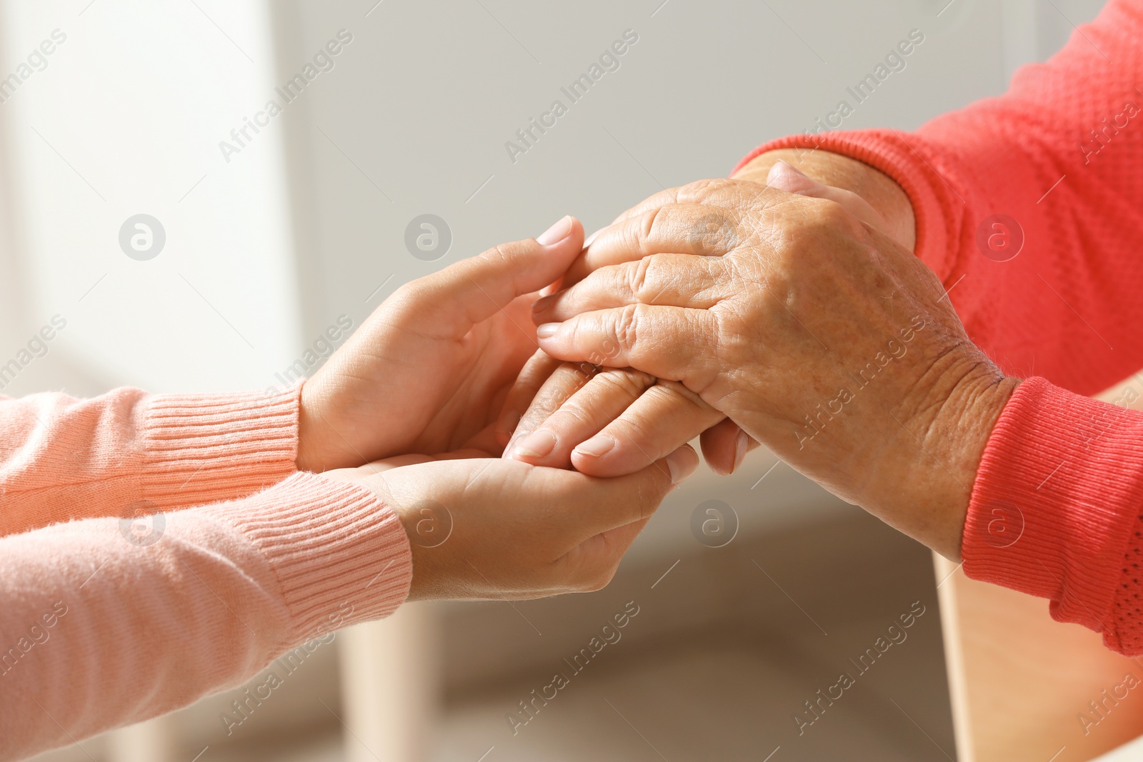 Photo of Helping hands on blurred background, closeup. Elderly care concept