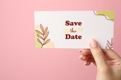 Photo of Woman holding beautiful card with Save the Date phrase on pink background, closeup