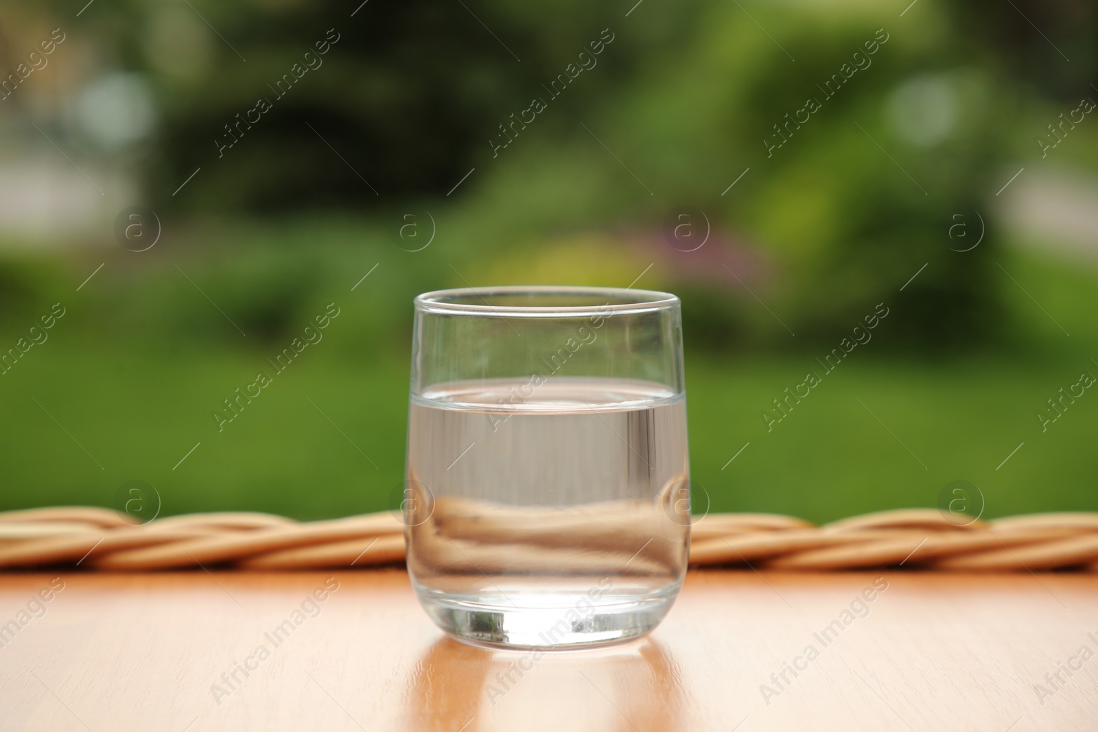 Photo of Glass of fresh water on wooden table outdoors