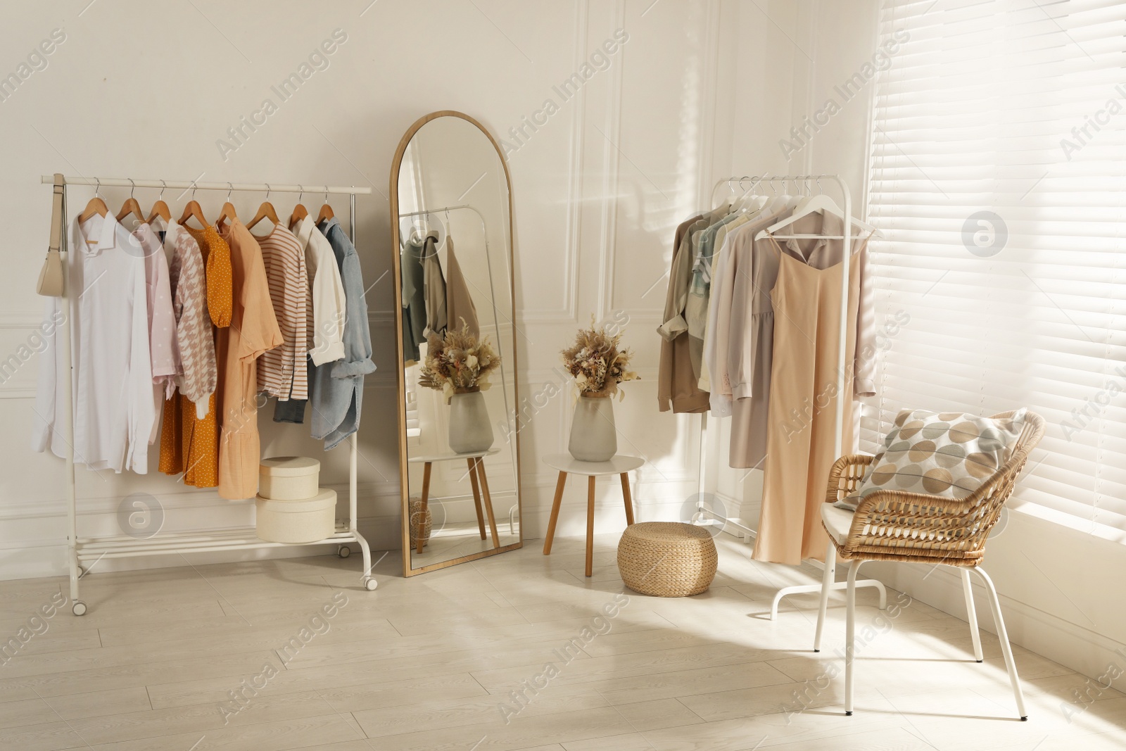 Photo of Modern dressing room interior with stylish clothes and beautiful dry flowers