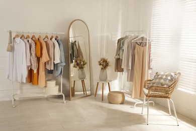 Photo of Modern dressing room interior with stylish clothes and beautiful dry flowers
