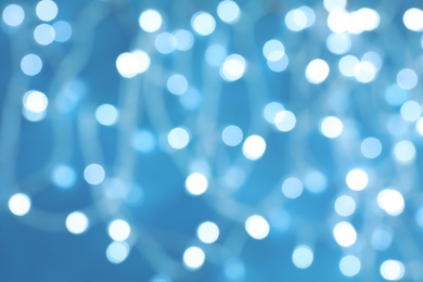 Blurred view of Christmas lights on color background