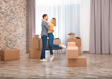 Photo of Couple hugging near moving boxes in their new house