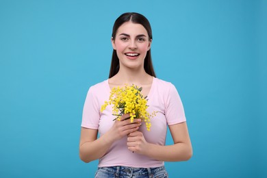 Happy young woman with beautiful bouquet on light blue background