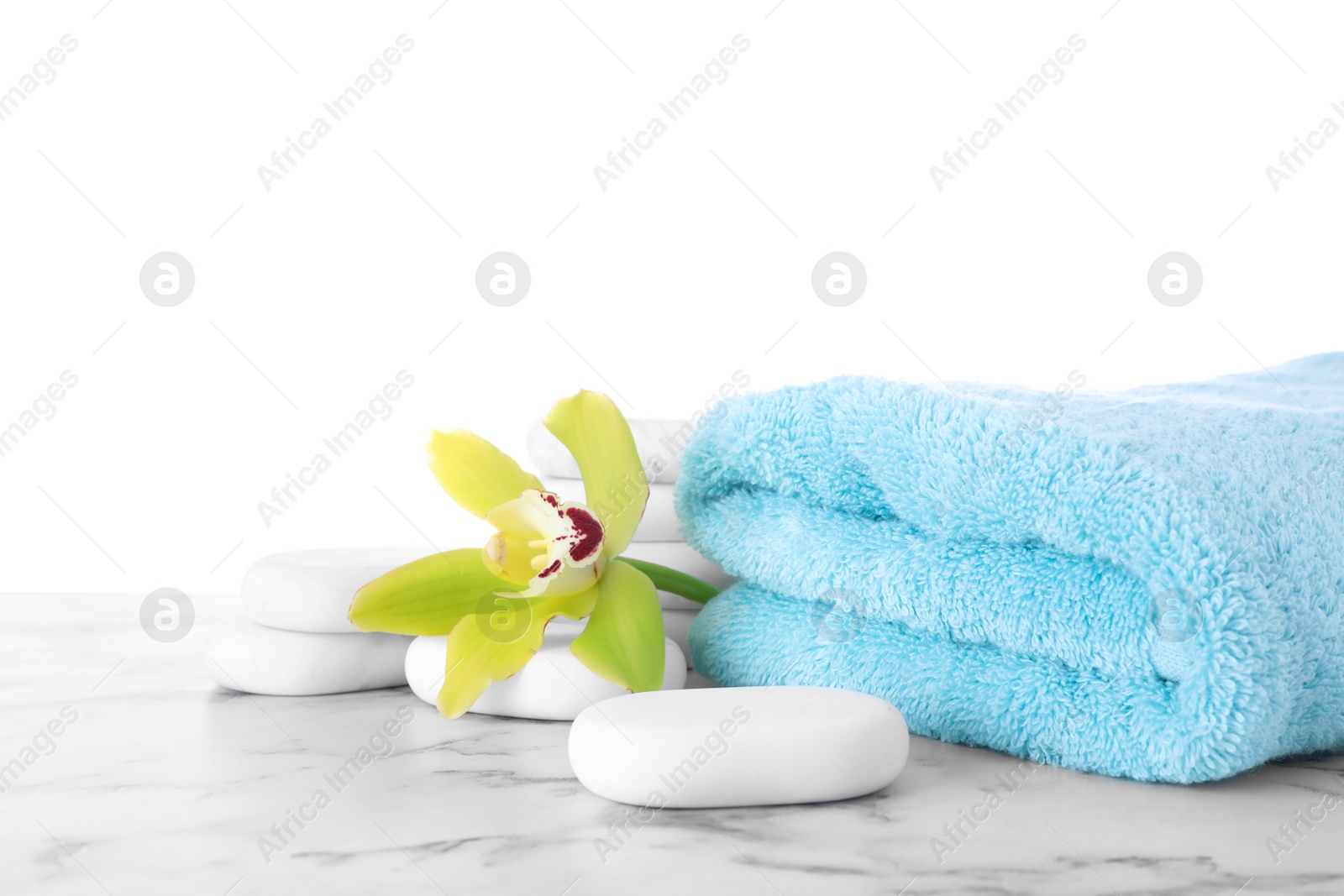 Photo of Fresh towel, spa stones and exotic flower on marble table against white background