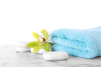 Photo of Fresh towel, spa stones and exotic flower on marble table against white background