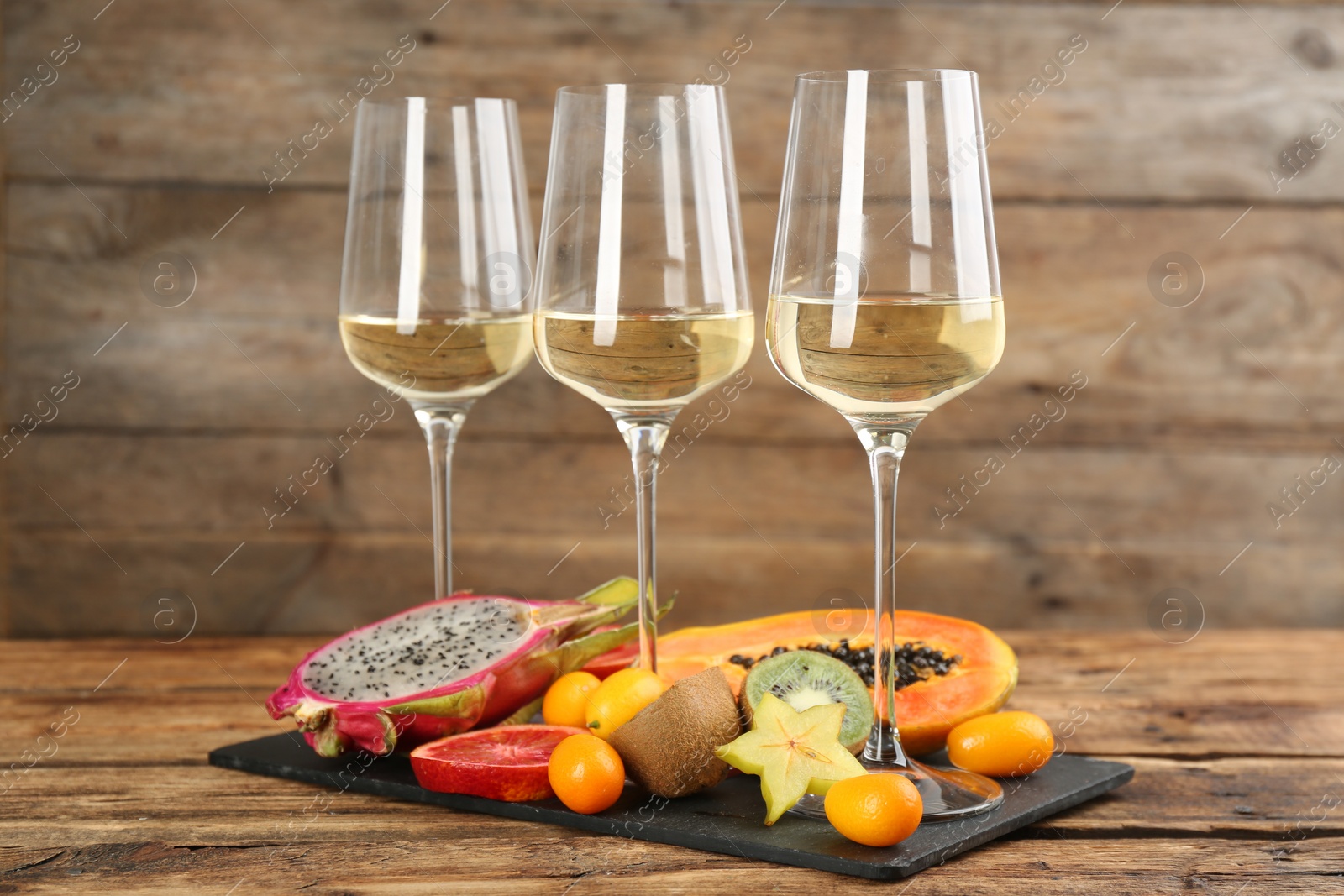 Photo of Delicious exotic fruits and wine on wooden table