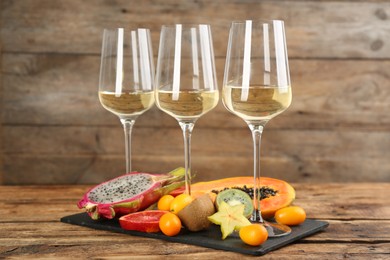 Delicious exotic fruits and wine on wooden table