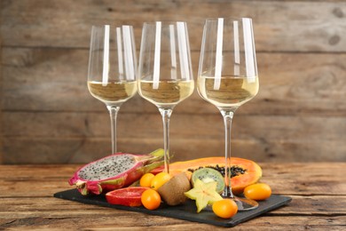 Photo of Delicious exotic fruits and wine on wooden table