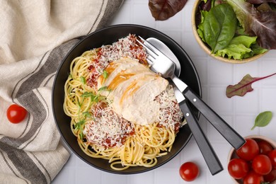 Delicious pasta with tomato sauce, chicken and parmesan cheese on white tiled table, flat lay