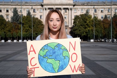 Photo of Young woman with poster protesting against climate change on city street