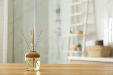 Reed air freshener on wooden table in bathroom. Space for text