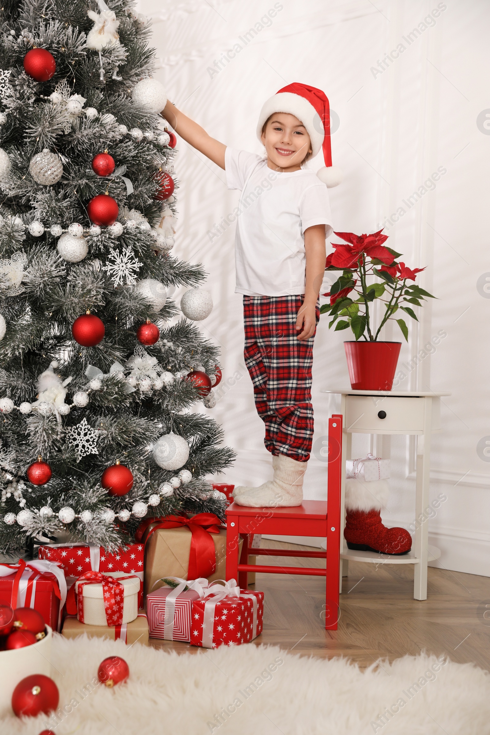 Photo of Cute little girl decorating Christmas tree at home