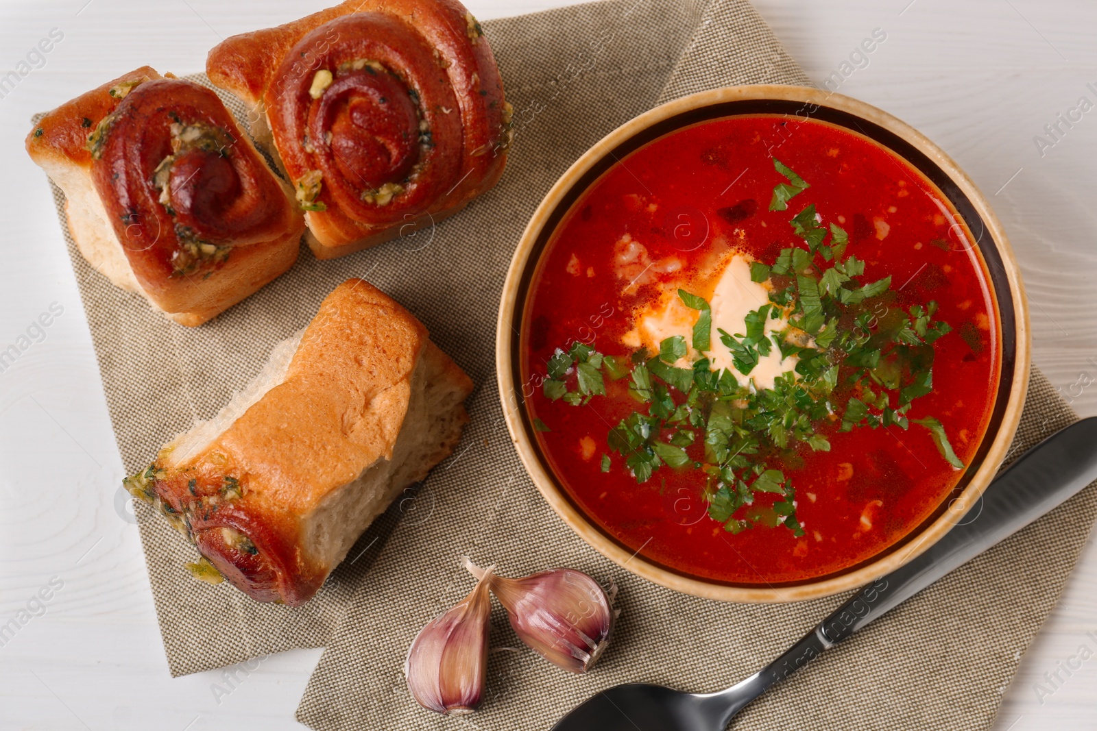 Photo of Delicious borsch served with pampushky on white wooden table, top view. Traditional Ukrainian cuisine