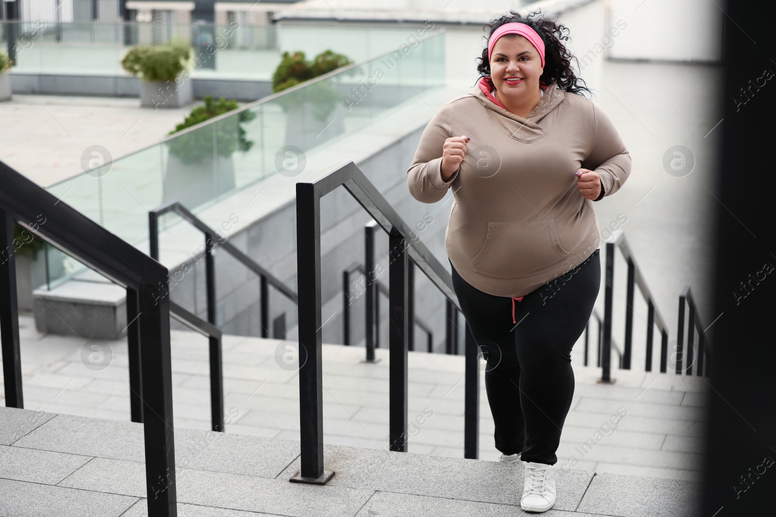 Photo of Beautiful overweight woman running up stairs outdoors