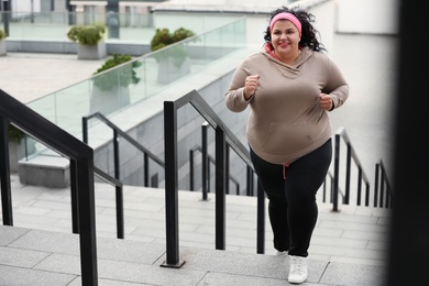 Beautiful overweight woman running up stairs outdoors