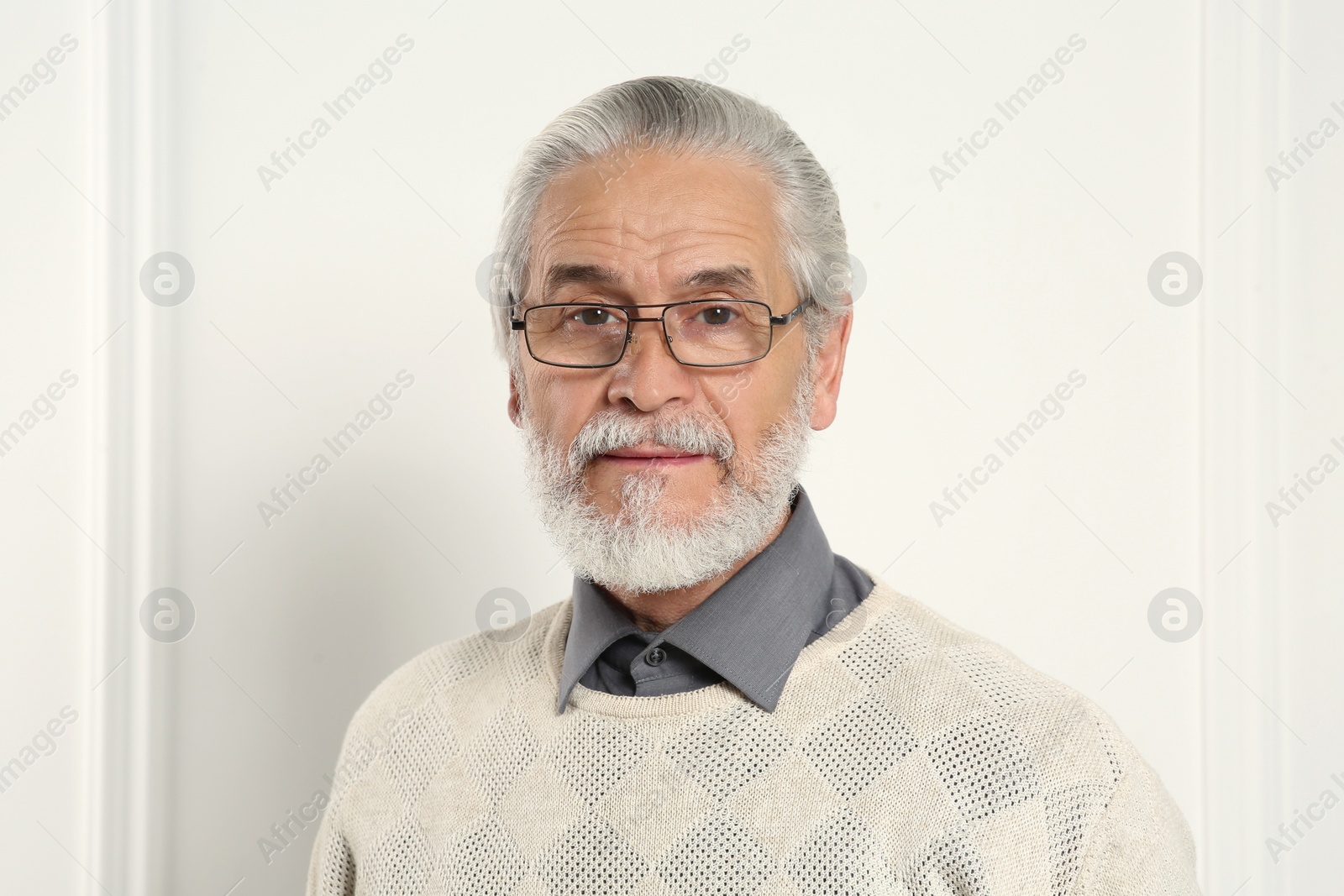 Photo of Portrait of handsome senior man in eyeglasses near white wall