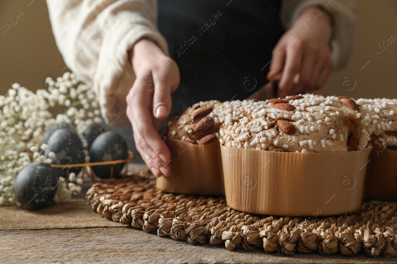 Photo of Woman taking delicious Italian Easter dove cake (traditional Colomba di Pasqua) at wooden table, closeup