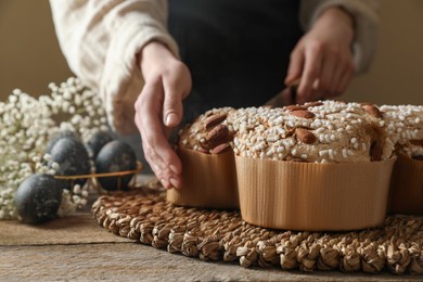 Woman taking delicious Italian Easter dove cake (traditional Colomba di Pasqua) at wooden table, closeup