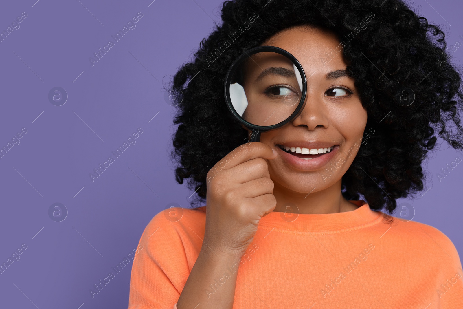 Photo of Woman looking through magnifier glass on purple background, space for text