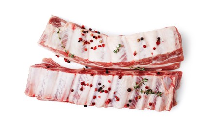 Photo of Raw pork ribs with thyme and peppercorns isolated on white, top view