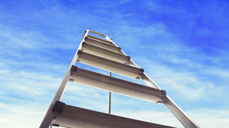 Metal stepladder against blue sky with clouds, low angle view. Banner design