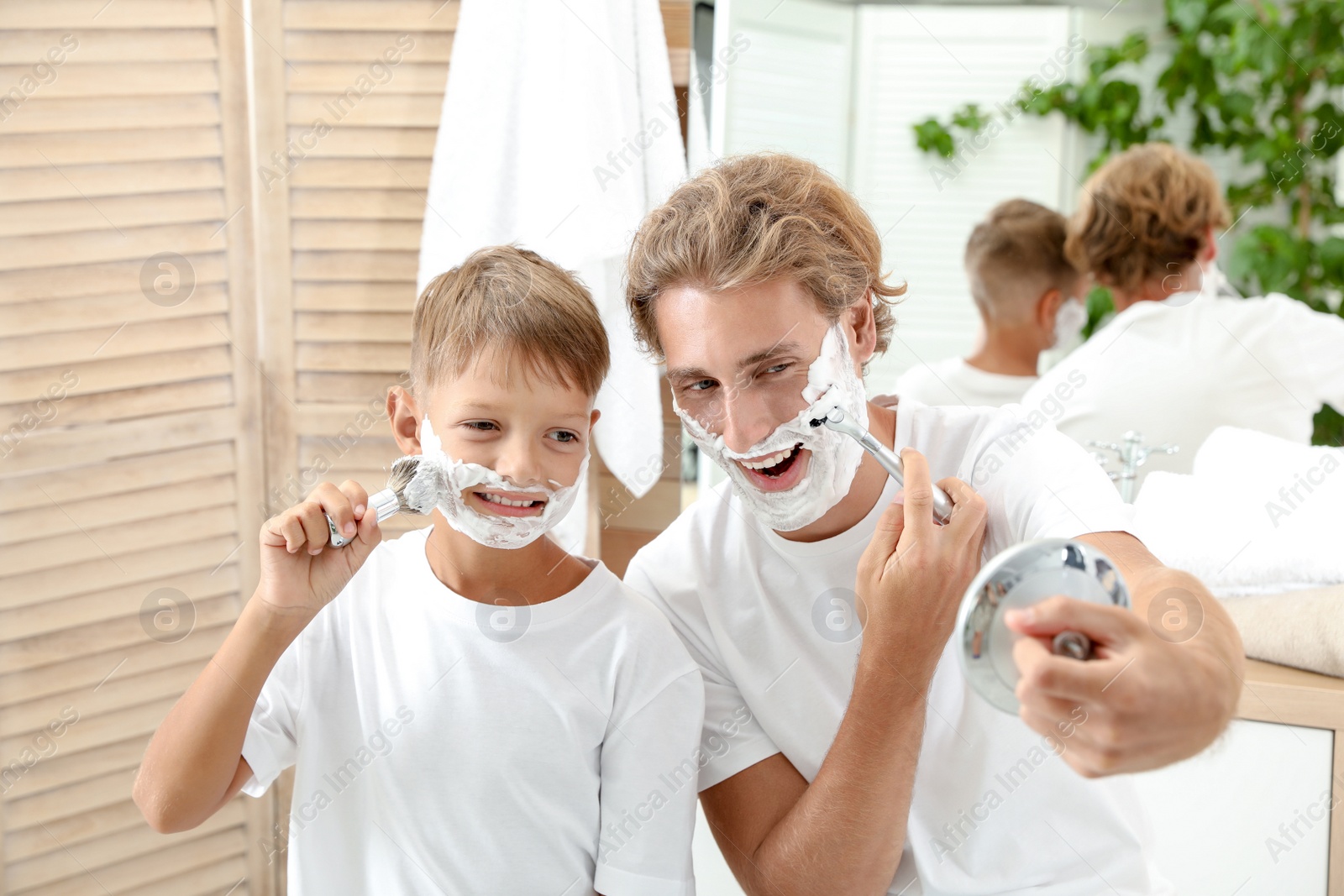 Photo of Father and son shaving together in bathroom