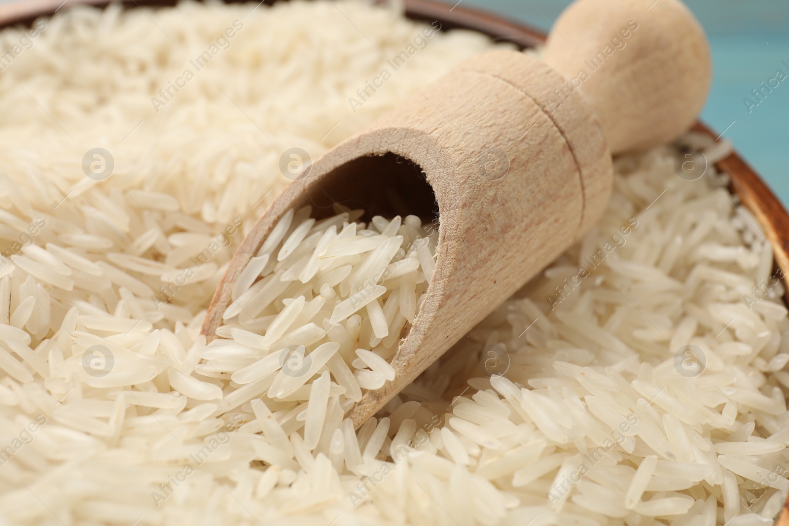 Photo of Raw basmati rice in bowl and wooden scoop, closeup