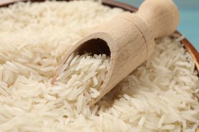 Photo of Raw basmati rice in bowl and wooden scoop, closeup