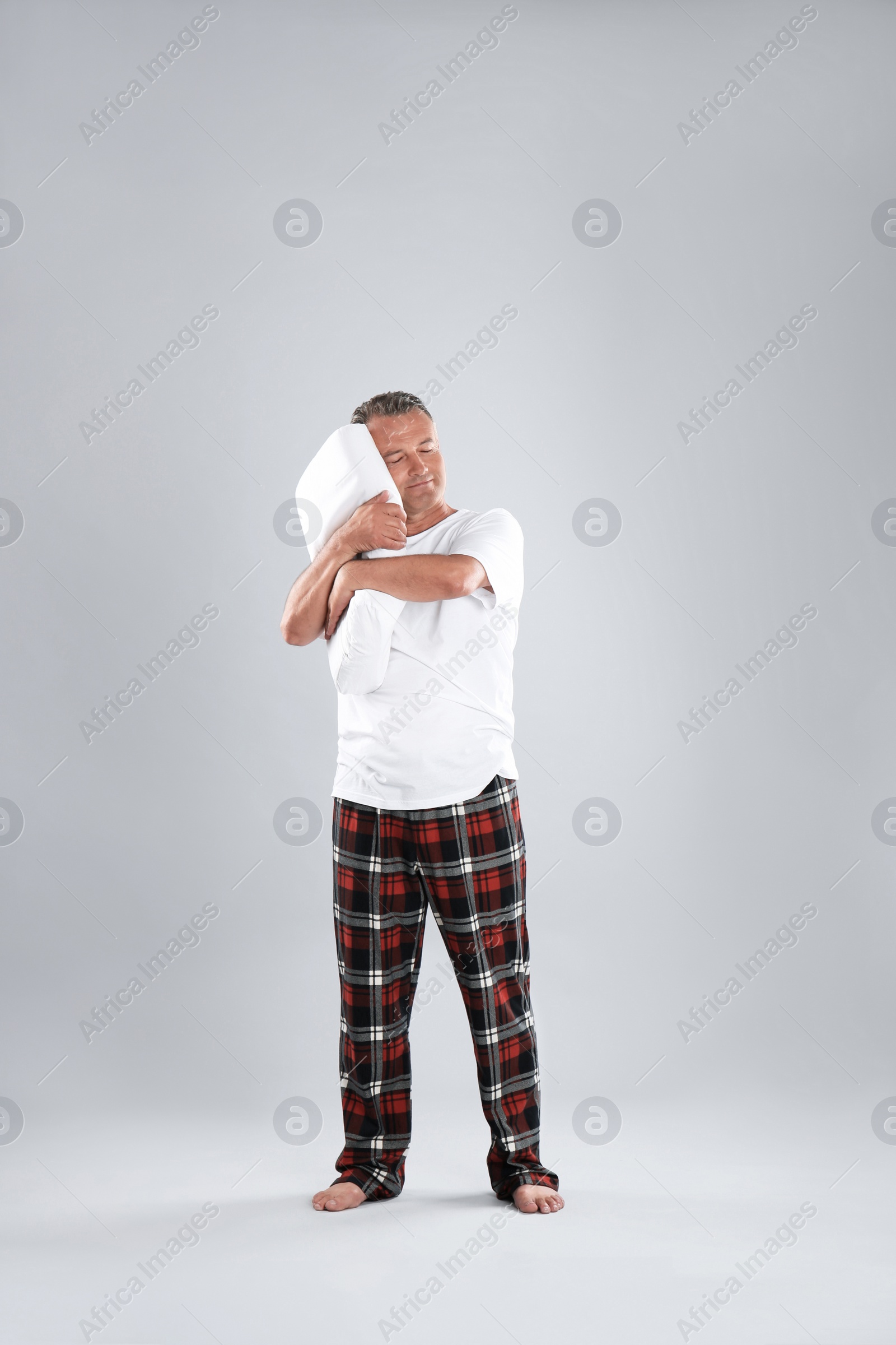 Photo of Man holding soft pillow on light background