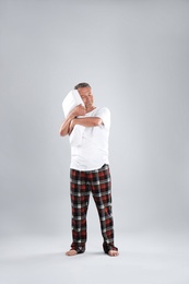 Photo of Man holding soft pillow on light background