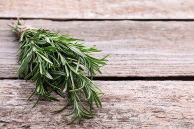 Photo of Bunch of fresh rosemary on wooden table, closeup. Space for text