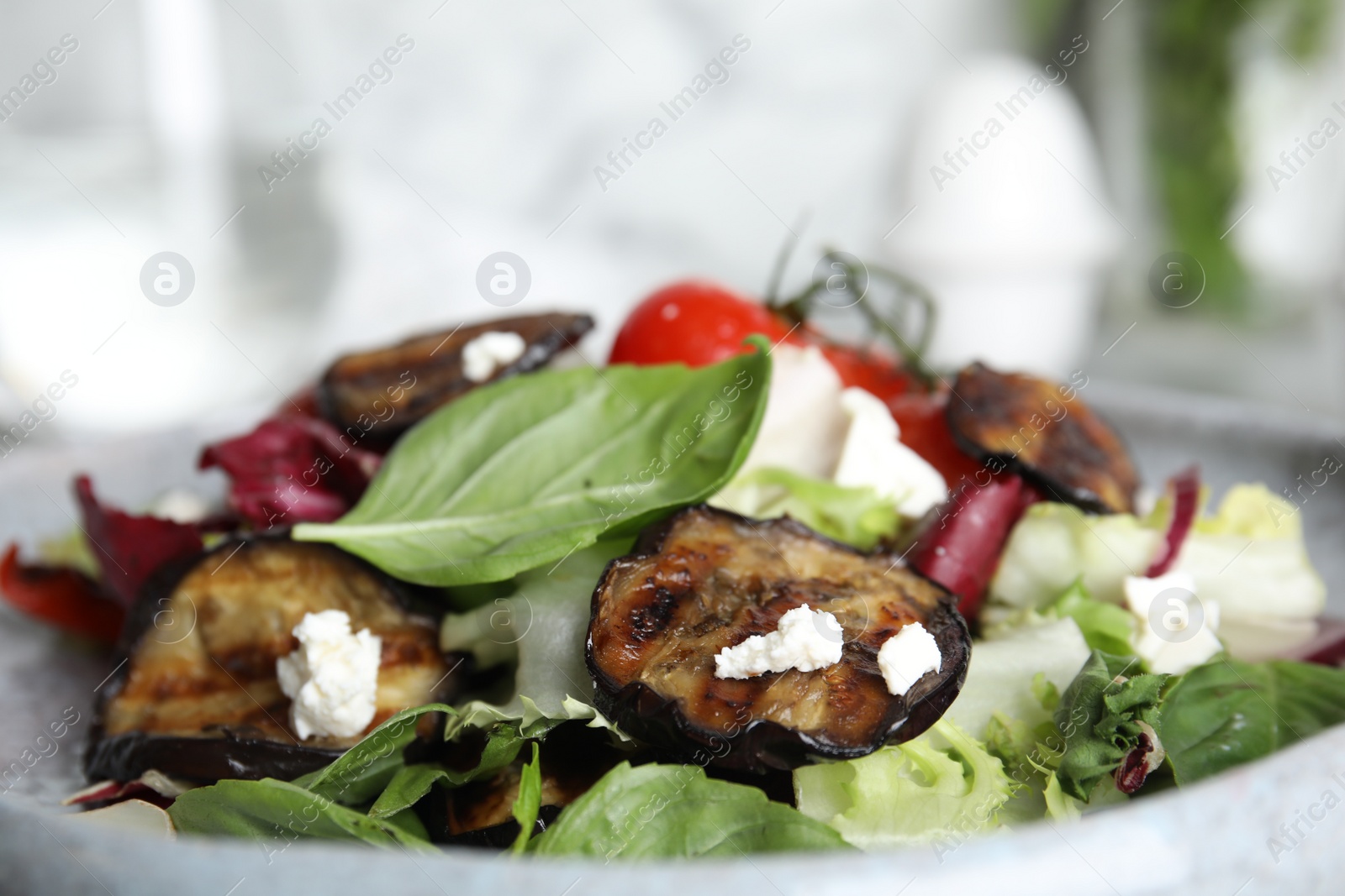 Photo of Delicious salad with roasted eggplant, basil and cheese on plate, closeup