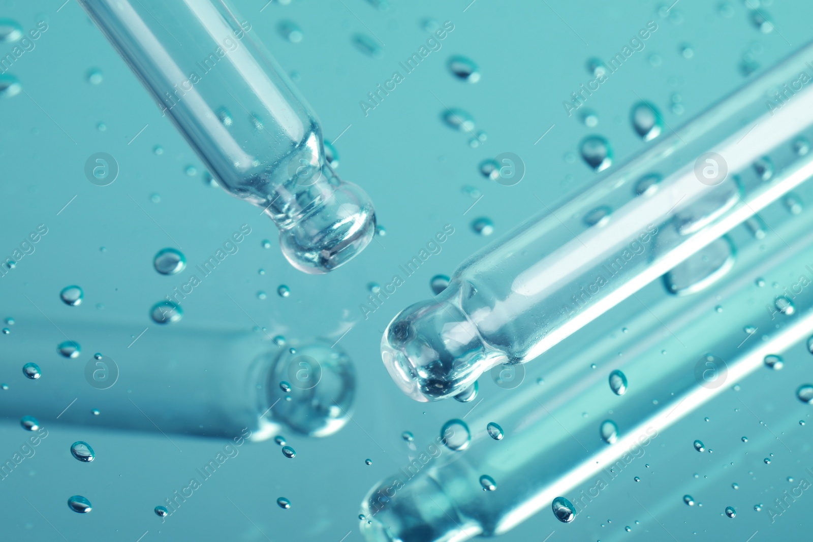 Photo of Pipettes near serum drops on beautiful mirror, closeup. Color tone effect