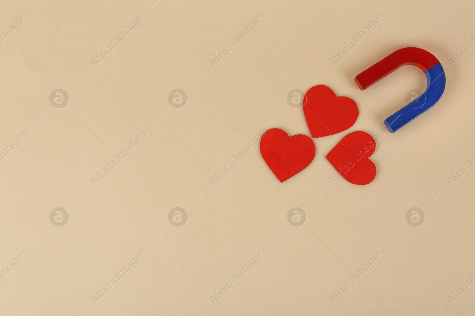 Photo of Magnet and red hearts on beige background, flat lay. Space for text