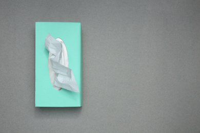 Box of paper tissues on grey background, top view. Space for text