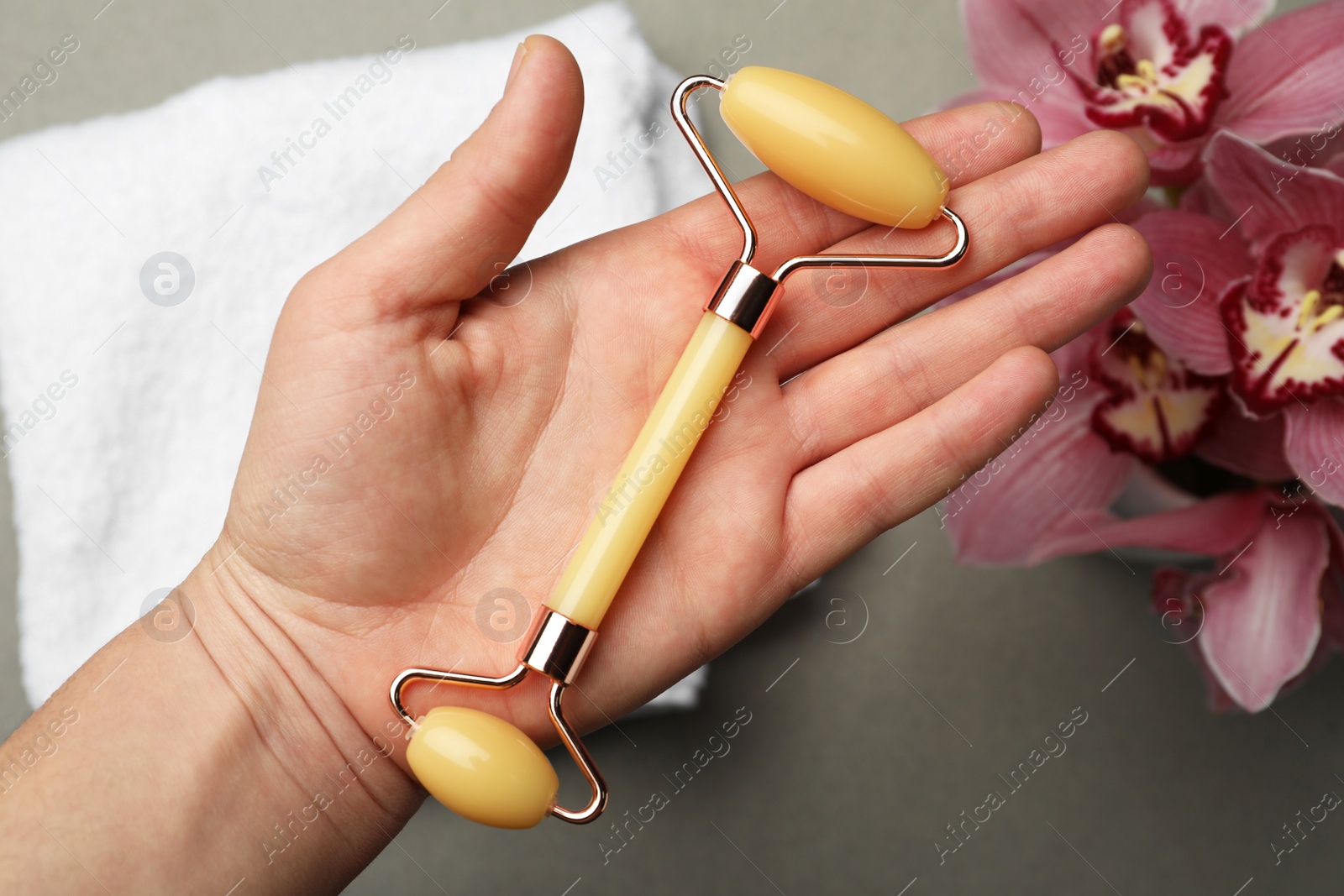 Photo of Woman with natural jade face roller on grey background, top view