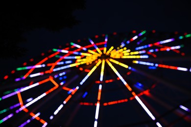 Photo of Blurred view of beautiful glowing Ferris wheel against dark sky